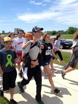 Hunter Gandee, 14, walks in Saline, Mich., on Sunday, June 8, 2014, during the second day of his two-day, 40-mile trek. Titled the Cerebral Palsy Swagger, the walk hoped to raise awareness for the muscle disorder that affects his 7-year-old brother, Braden, who was on his brother's back for the entirety of their journey from Temperance, Mich., to Ann Arbor, Mich. (AP Photo/Mike Householder) / AP
